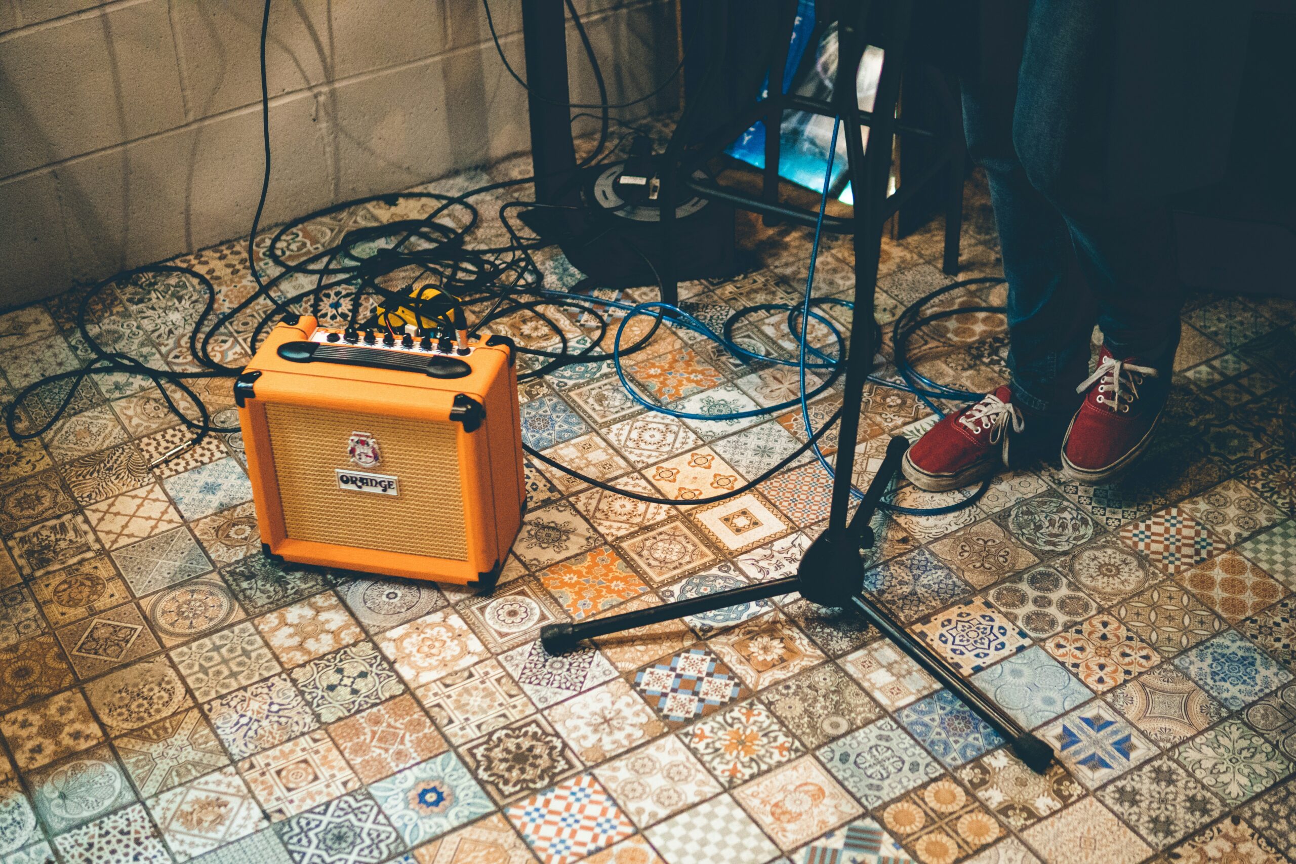 A small orange guitar amp on a tiled floor.