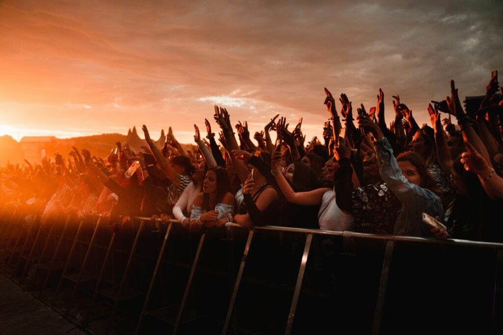 A crowd of people waiting for a concert at sunset.